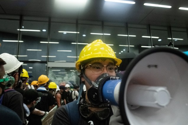 Manifestante usa um megafone enquanto outros quebram as portas e janelas de vidro da sede do governo em Hong Kong, no 22º aniversário da transferência da cidade da Grã-Bretanha para a China - 01/07/2019