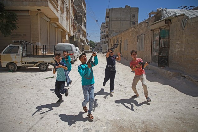 Meninos sírios brincam com armas de plástico no primeiro dia do festival religioso muçulmano de Eid al-Adha, em al-Dana, na região de Idlib controlada pelos rebeldes, perto da fronteira com a Turquia.