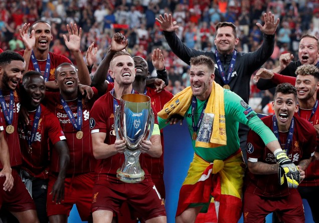 Henderson, capitão do Liverpool, levanta o troféu junto com a equipe ao comemorar a conquista da Supercopa da UEFA contra o Chelsea.