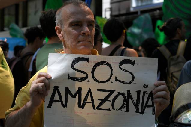 Um ativista climático segura uma placa com a inscrição "SOS Amazon" durante uma manifestação em Barcelona, na Espanha