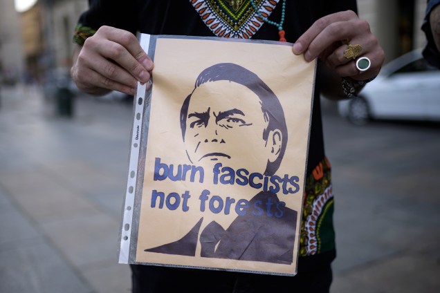 Um manifestante segura um cartaz com a inscrição "Queime fascistas, não florestas" durante uma manifestação na Piazza Castello, em Turim, na Itália