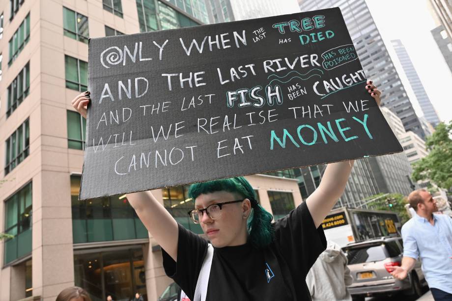 Ativista levanta uma placa de protesto em frente ao Consulado Geral do Brasil, Nova York, nos EUA