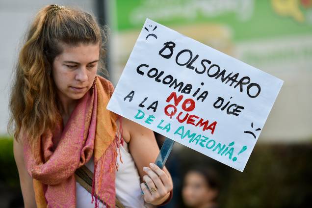Um ativista da mudança climática segura uma placa com a inscrição "Bolsonaro, a Colômbia diz NÃO à queima da Amazônia", durante um protesto em frente ao consulado brasileiro em Cali, Colômbia