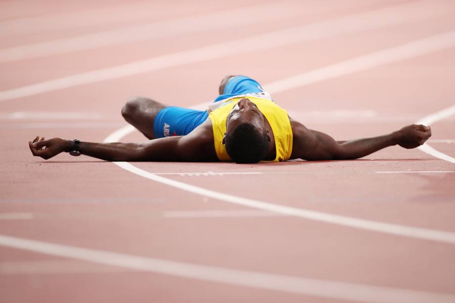 Jonathan Busby, de Aruba, encontra-se na pista depois de ser ajudado na linha de chegada nas mangas de 5000 metros masculinos, em Doha, no Catar