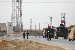 Russian and Syrian national flags flutter on military vehicles near Manbij