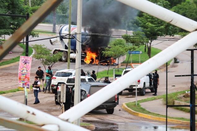 Homens armados próximos a um caminhão em chamas durante confrontos com as autoridades após a apreensão de Ovidio Guzmán, filho de El Chapo, em Culiacán - 17/10/2019