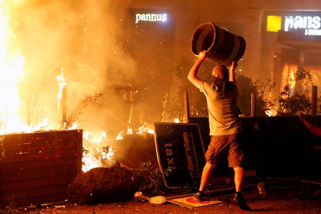 Durante os protestos da greve geral, um manifestante catalão usa mais uma lata de lixo para alimentar o fogo - 18/10/2019 Durante os protestos da greve geral, um manifestante catalão usa mais uma lata de lixo para alimentar o fogo - 18/10/2019