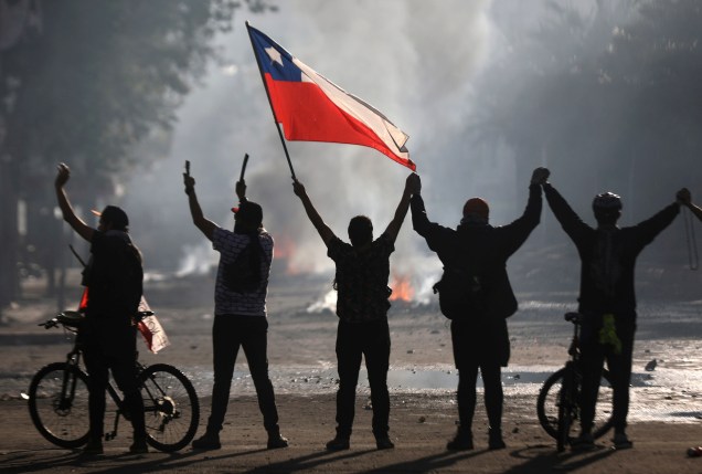 Chilenos seguram a bandeira nacional durante protestos em Santiago: repressão ao velho estilo - 21/10/2019