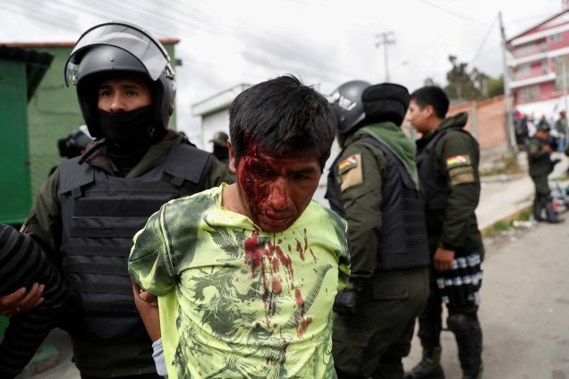 Um policial detém um homem ferido durante os confrontos entre partidários do presidente boliviano Evo Morales, e partidários da oposição, em La Paz.