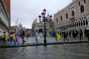 People walk on a catwalk in the flooded St.Mark’s Square during a period of seasonal high water