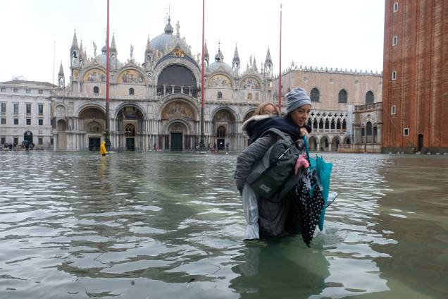Uma mulher carregando uma crianças nos braços na Preça de São Marcos, que está inundada, em Veneza - 12/11/2019