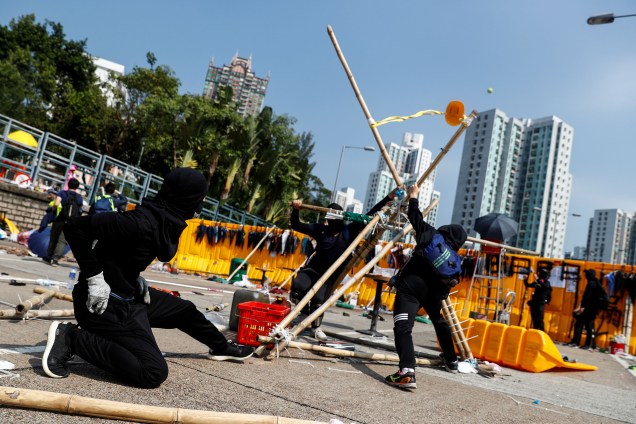 Manifestantes estudantis usam um estilingue gigante improvisado para arremessar bolas de tênis através de uma barricada como lazer na Universidade Batista de Hong Kong, China