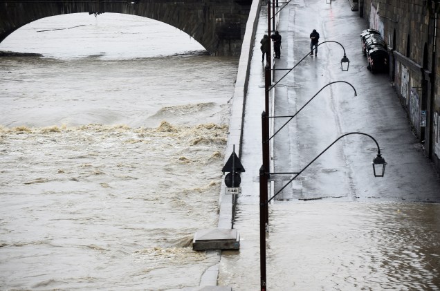 Pessoas caminham próximo às margens do rio Pó, quando ele atinge um nível crítico, enquanto chuvas torrenciais varrem a Itália inundando partes do centro da cidade de Turim, na Itália — 24/11/2019