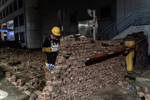Um manifestante pró-democracia constrói uma parede de tijolos durante uma manifestação na Universidade Chinesa de Hong Kong
