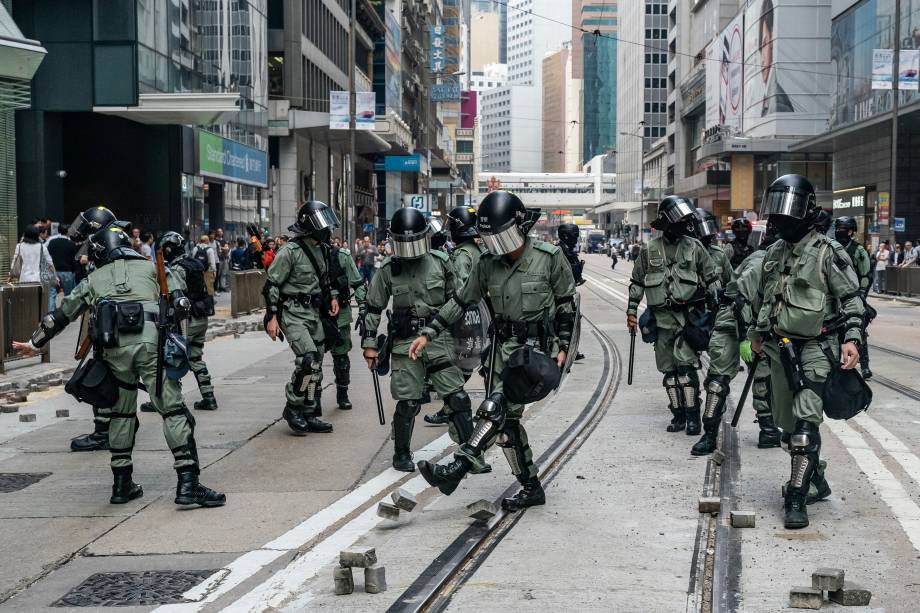 A polícia de choque limpa tijolos em uma rua onde manifestantes tentaram bloquear o tráfego no Distrito Central em Hong Kong, China