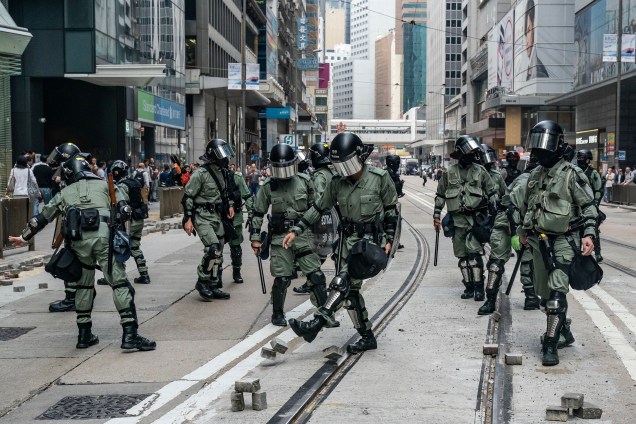 A polícia de choque limpa tijolos em uma rua onde manifestantes tentaram bloquear o tráfego no Distrito Central em Hong Kong, China