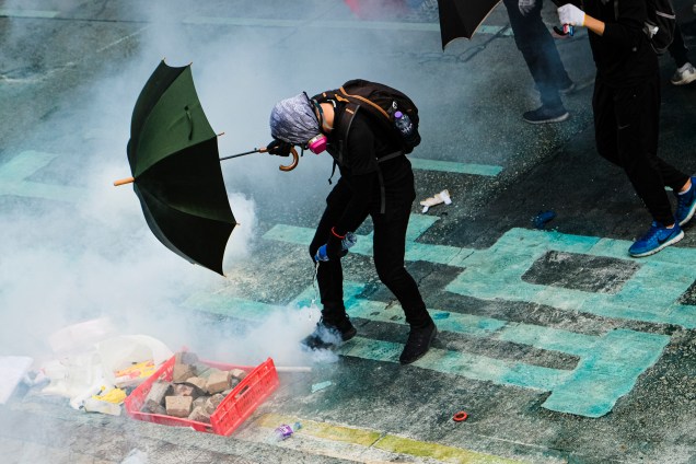 Um manifestante coloca água em uma lata de gás lacrimogêneo durante a manifestação em Hong Kong