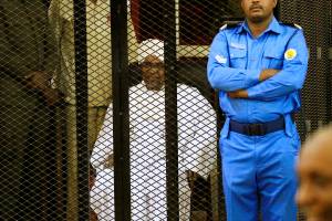 Sudanese former president Omar Hassan al-Bashir sits inside a cage during the hearing of the verdict that convicted him of corruption charges in a court in Khartoum