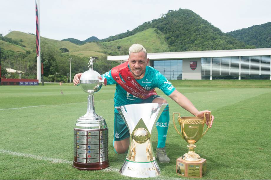 Diego Alves posa com as taças conquistadas na temporada: Libertadores, Brasileirão e Campeonato Carioca, no Ninho do Urubu