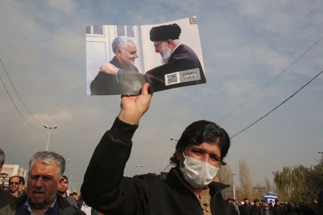 Um iraniano ergue uma foto do Supremo líder, aiatolá Ali Khamenei, ao lado do general Qassem Soleimani, morto em um ataque aéreo dos Estados Unidos - 03/01/2020