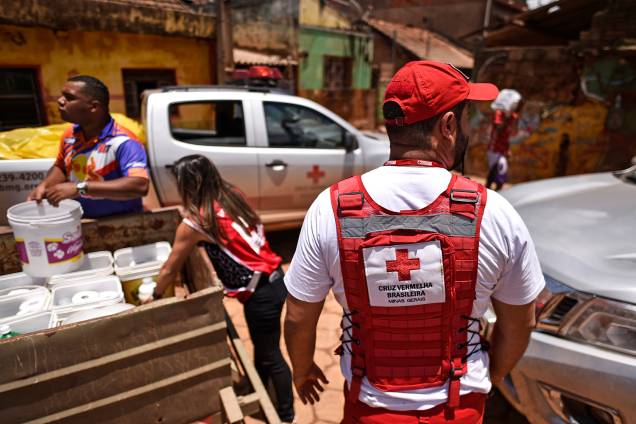 Membros da Cruz Vermelha do Brasil distribuem água e material de limpeza para os moradores locais, após o transbordamento do córrego Da Prata devido a chuvas torrenciais, em Raposos, região metropolitana de Belo Horizonte, em 28 de janeiro