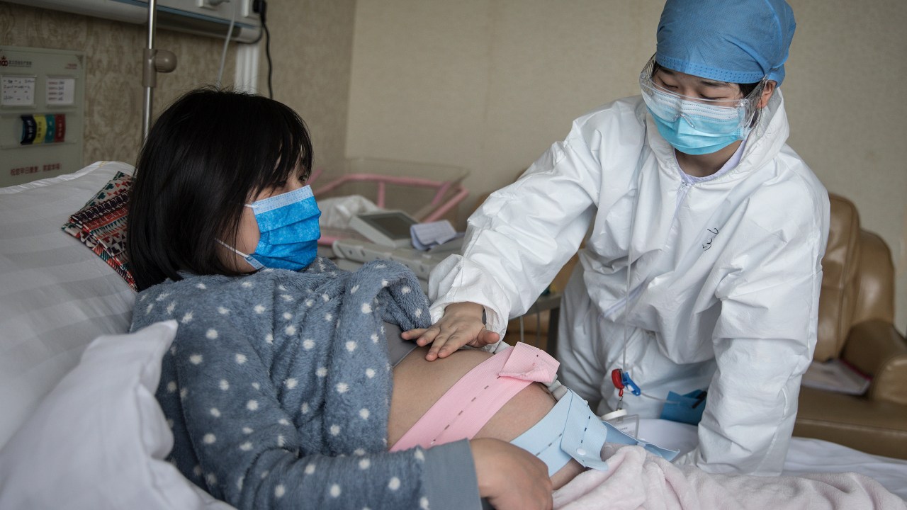 Enfermeira atende mulher grávida em Wuhan, na China