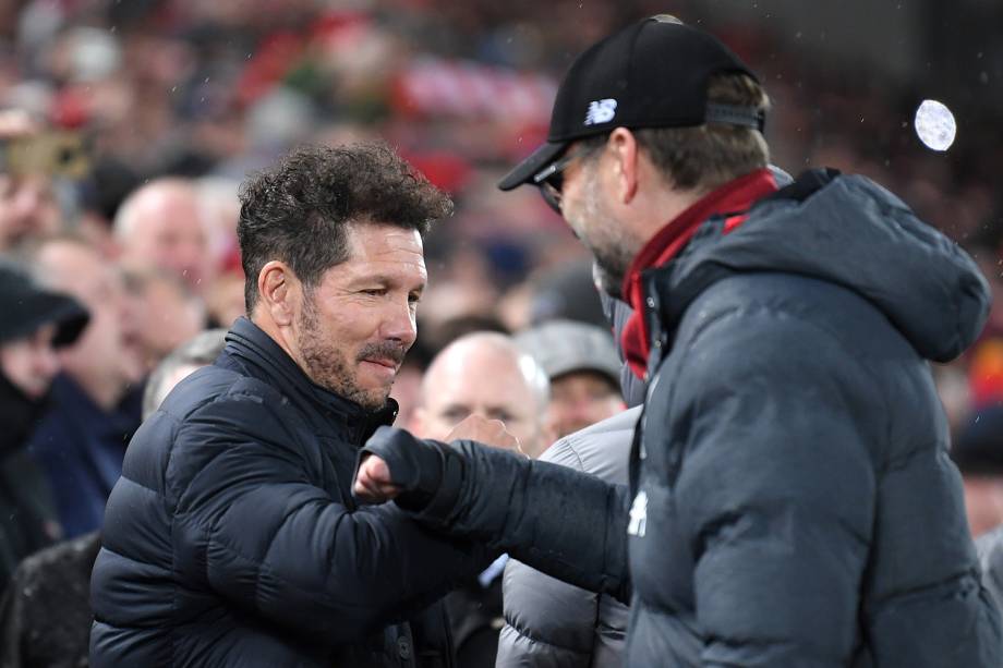 Diego Simeone, do Atlético de Madrid e Jurgen Klopp, do Liverpool, evitam o toque de mão ao se cumprimentarem antes do confronto em Anfield