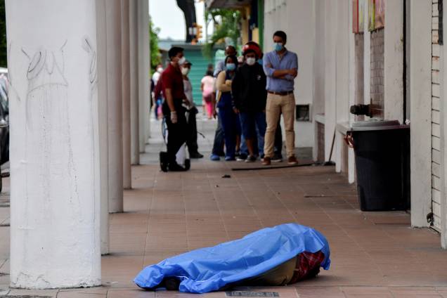 Pessoas ficam na fila em frente a uma loja perto do cadáver de um homem que desmaiou na calçada, durante o surto de coronavírus, em Guayaquil, no Equador