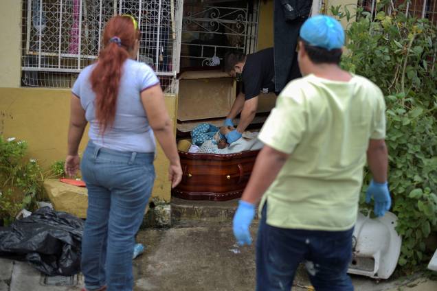 O corpo de uma mulher é colocado dentro de um caixão após morrer em casa durante o surto do coronavírus, em Guayaquil, no Equador