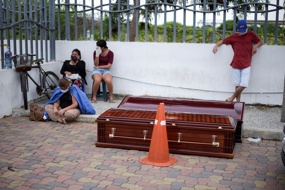 Pessoas esperam ao lado de caixões do lado de fora do Hospital Geral Guasmo Sur, em Guayaquil, no Equador