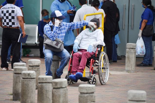 Um homem tem sua máscara de respirar ajustada enquanto espera do lado de fora do Hospital Geral Guasmo Sur, em Guayaquil, no Equador