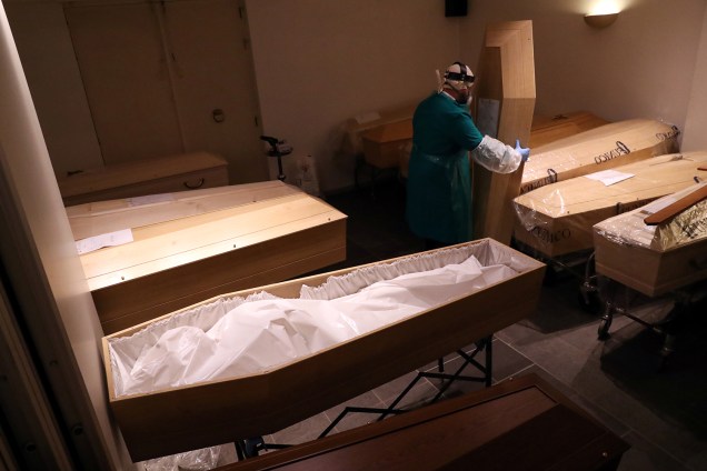 Preparação: Agente funerário usando traje de proteção segura a tampa de um esquife em Bruxelas, na Bélgica