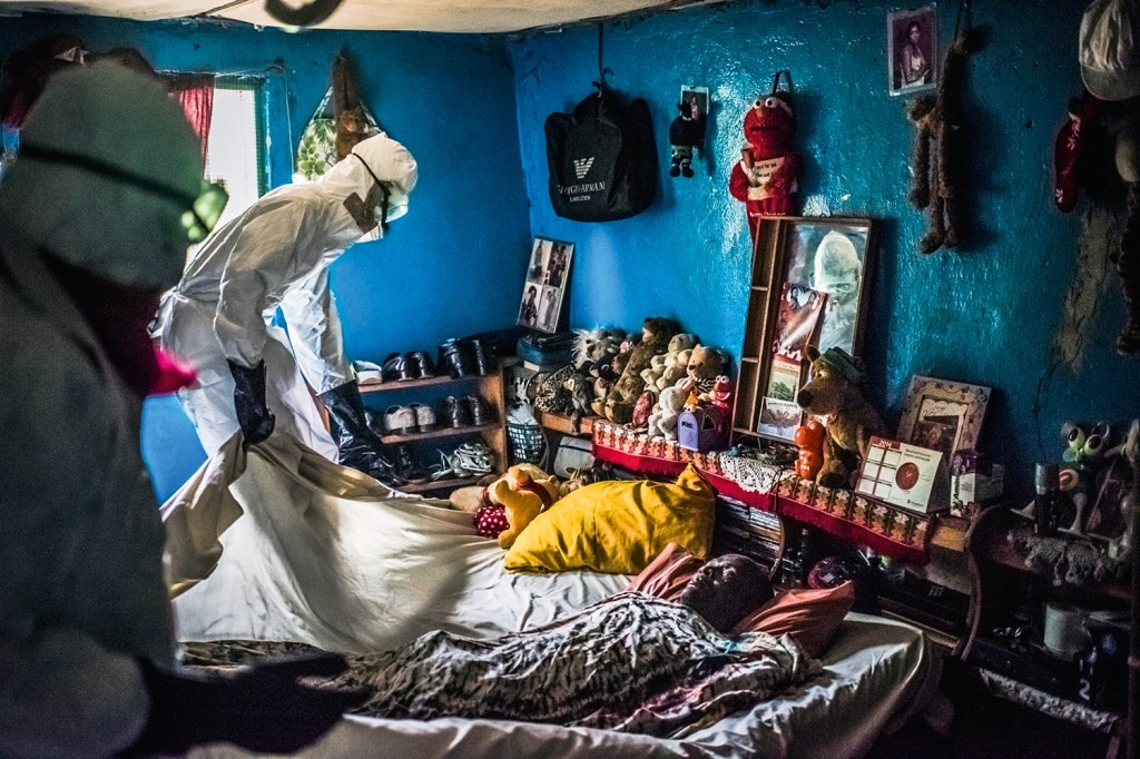 Homem com roupa de proteção retira um corpo de alguém vitima do ebola