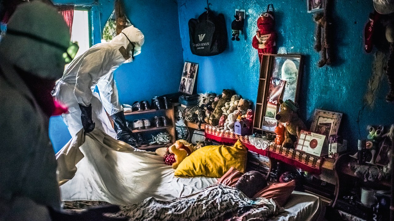Homem com roupa de proteção retira um corpo de alguém vitima do ebola