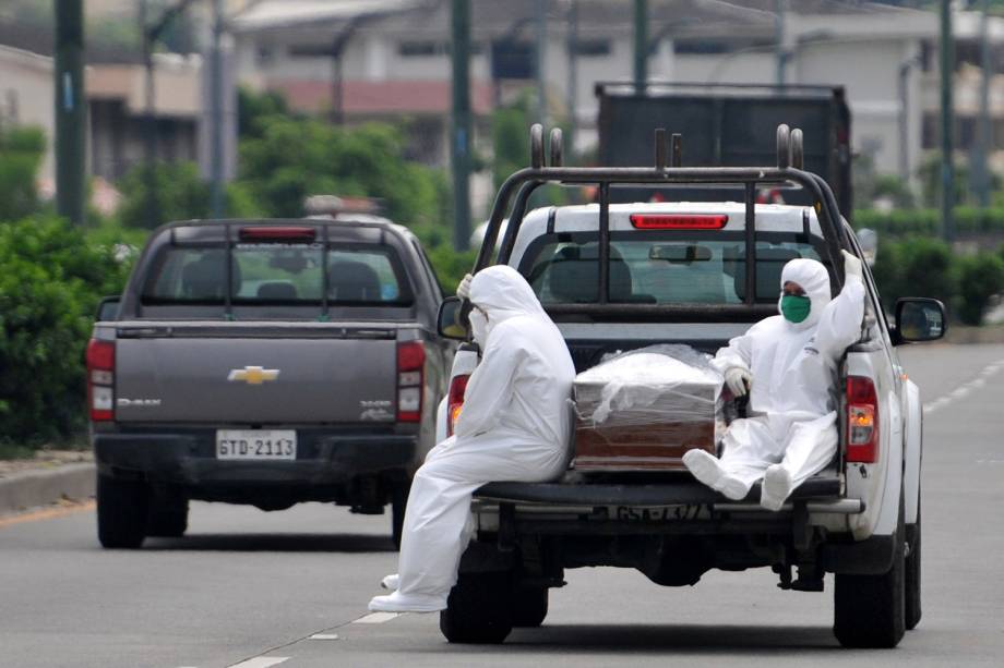 Transporte possível: Pessoas vestindo trajes de proteção acompanham um esquife em caminhonete perto do hospital Los Ceibos, em Guayaquil, Equador