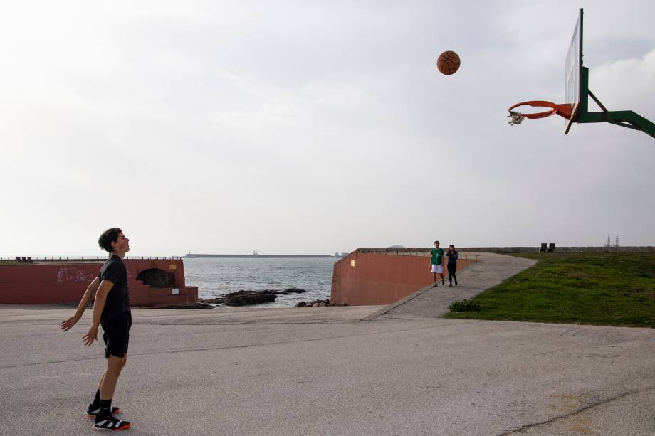 Criança joga basquete na praia de Matosinhos, em Portugal. Por lá, esportes ao ar livre estão liberados, mas apenas de forma individual