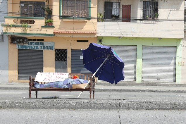 Indigência: O corpo de María Zamora abandonado em banco público, com uma placa de pedido de ajuda, em uma das principais ruas de Guayaquil