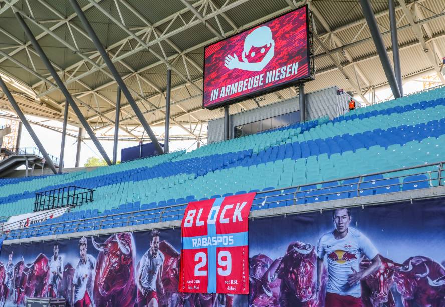 Nessa imagem, o telão do estádio lembra os presentes das melhores práticas sanitárias: "espirre nos cotovelos", diz a mensagem.