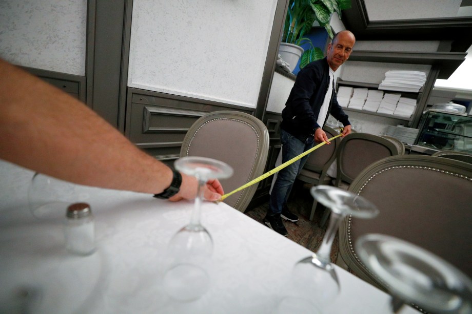 Proprietários do restaurante Nuova Fiorentina, em Roma, medem a distância entre as mesas para garantir a manutenção do distanciamento social entre os clientes.