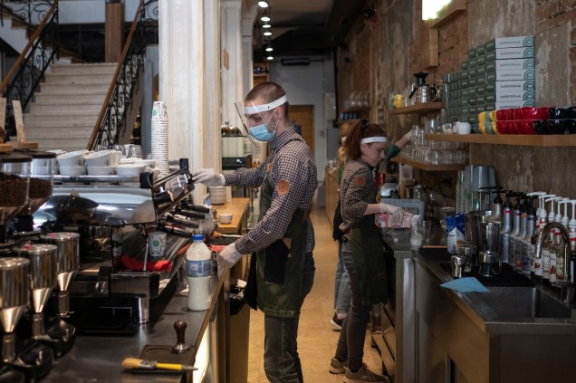 Barista usa uma máscara protetora enquanto prepara um cappuccino dentro de um café em Belgrado, na Sérvia. 