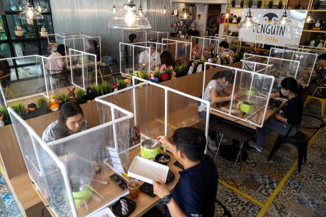 Restaurante em Bangkok, na Tailândia, usa uma barreira plástica para manter as medidas de distanciamento social entre os clientes.