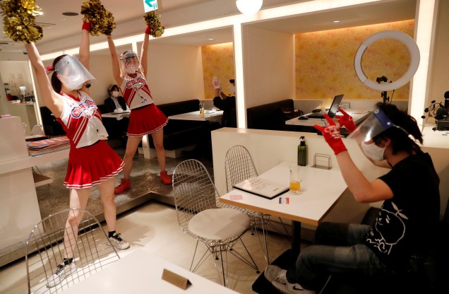Garçonetes usam máscaras protetoras, escudos e luvas enquanto fazem sus performance no restaurante temático 'Cheers One' em Tóquio, no Japão.