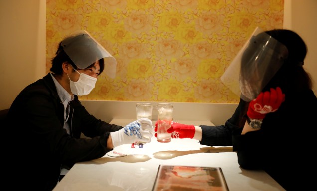 Clientes de um restaurante em Tóquio, no Jaão, usam máscaras, protetores faciais e luvas para prevenir infecções após o surto da Covid-19.