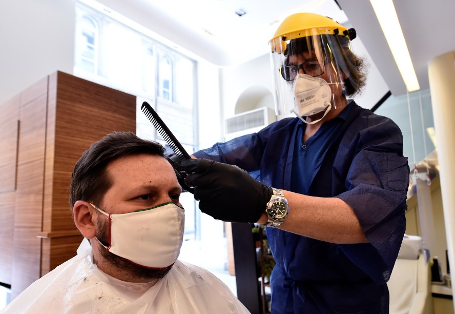 Cabeleireiro usa escudo protetor durante atendimento em salão de beleza em Milão, na Itália - 18/05/2020