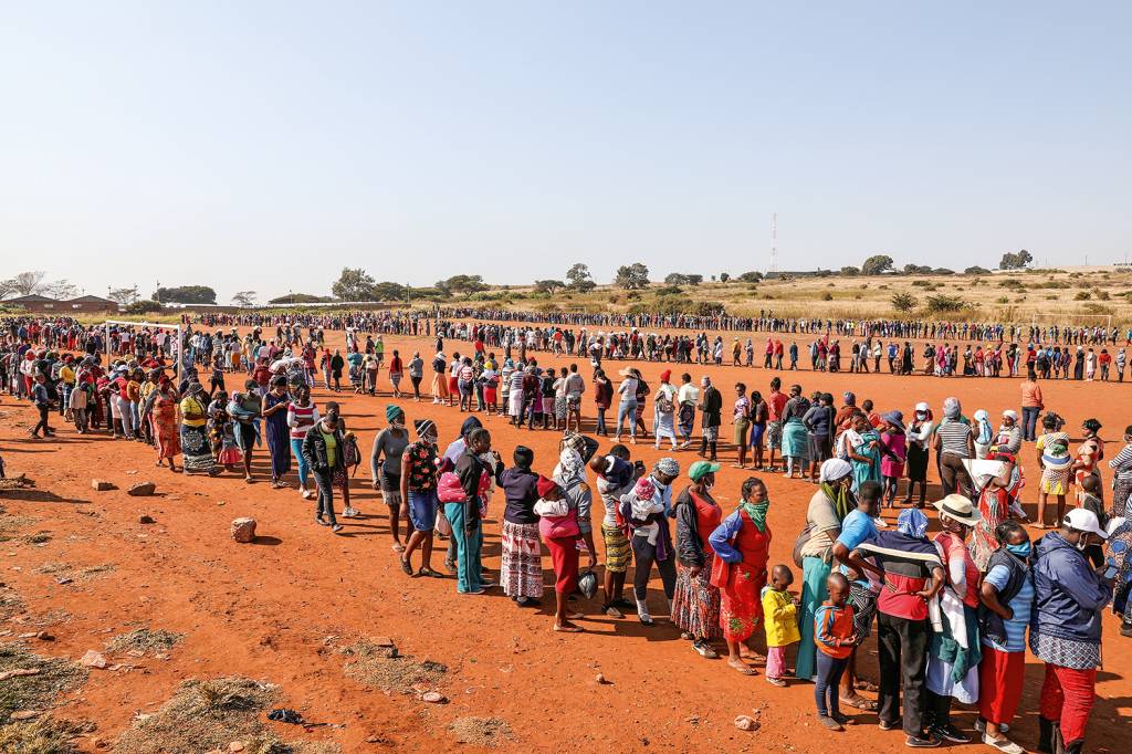 FOME DOBRADA - Fila para pegar alimentos na África do Sul: a crise pode levar milhões à pobreza extrema