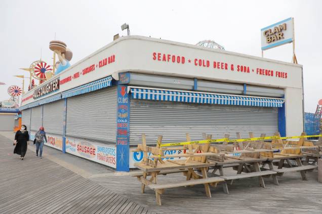 Memorial Day: Coney Island beach, em Nova York - 22/5/2020People walk by a closed restaurant on the boardwalk at Coney Island beach ahead of the Memorial Day weekend following the outbreak of the coronavirus disease (COVID-19) in Brooklyn, New York City, U.S., May 22, 2020.