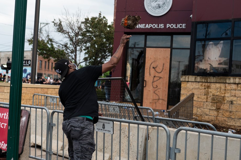 Um manifestante arremessa um pedaço de concreto no prédio da Delegacia de Polícia em Minneapolis, Minnesota