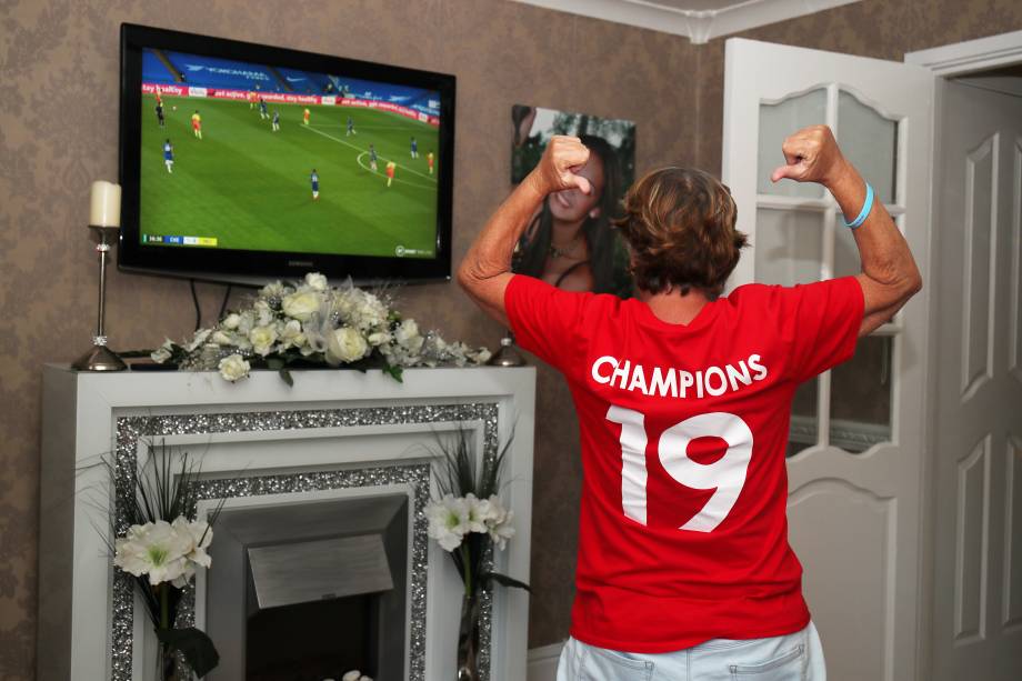 A torcedora do Liverpool, Emily Farley, comemora depois que o Chelsea vence o Manchester City enquanto assiste à partida na TV