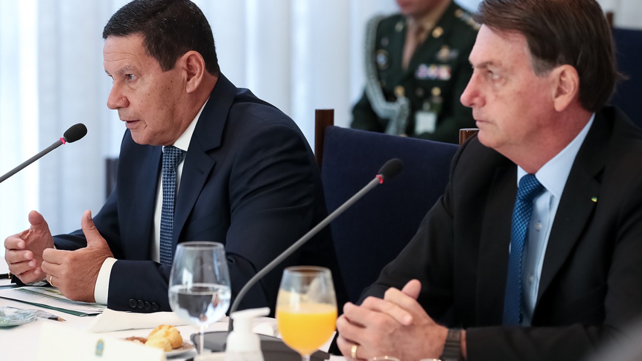 Como não pode demiti-lo, Bolsonaro cancela Mourão - Na imagem o presidente Jair Bolsonaro esta sentado ao lado do seu vice-presidente Hamilton Mourão, ao fundo é possível ver um militar.