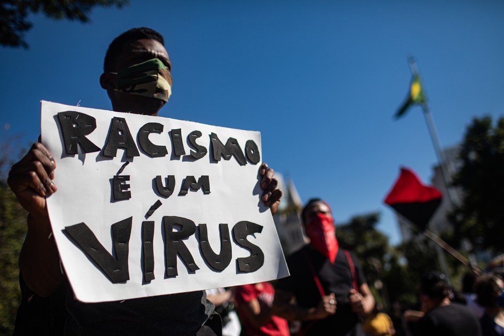 Um manifestante segura uma placa com a mensagem "Racismo é um virus" durante um protesto da Black Lives Matter no Largo da Batata, São Paulo